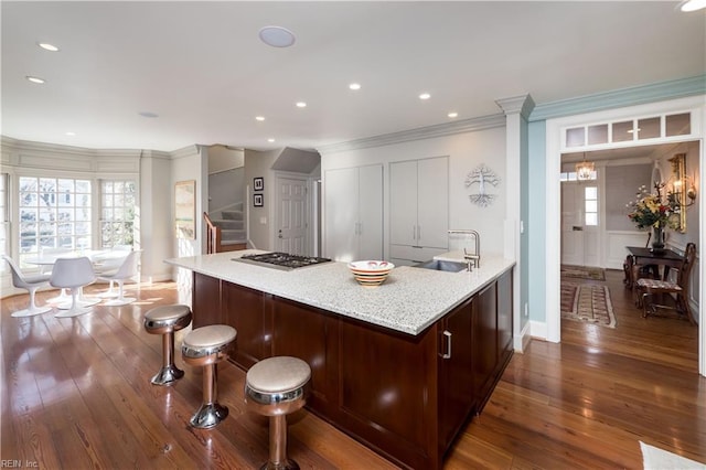 kitchen with plenty of natural light, dark wood-style flooring, a kitchen bar, stainless steel gas cooktop, and a sink