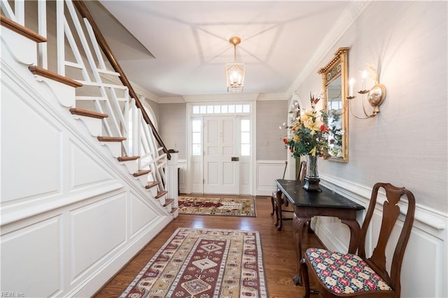 entryway with wainscoting, stairway, ornamental molding, dark wood-type flooring, and a decorative wall