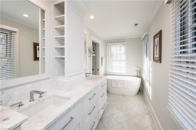 bathroom with crown molding, a freestanding bath, a sink, and double vanity