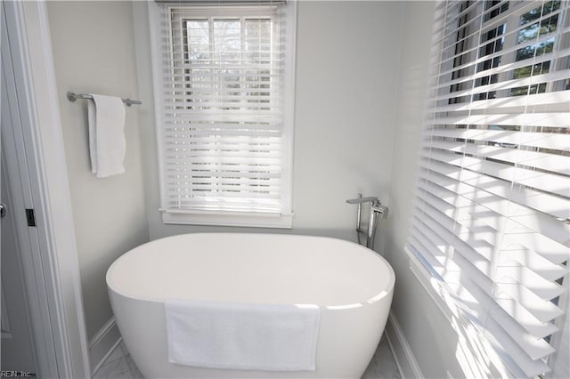 bathroom featuring a soaking tub and baseboards