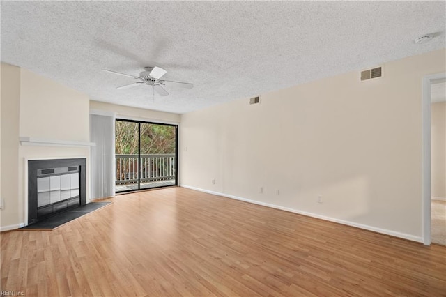 unfurnished living room featuring a glass covered fireplace, visible vents, and light wood-style floors