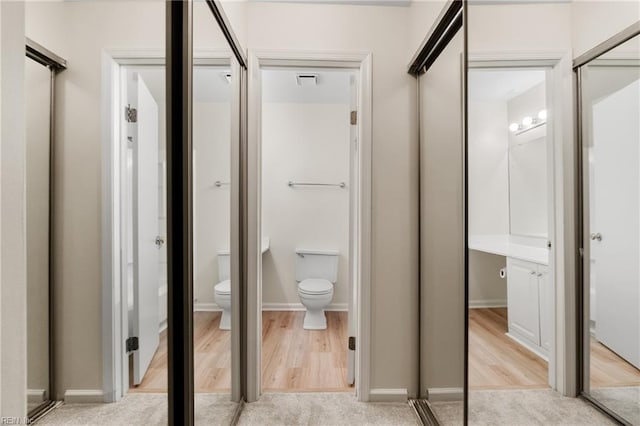 bathroom featuring toilet, baseboards, visible vents, and wood finished floors