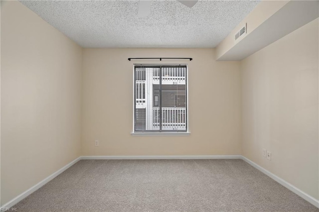 empty room with baseboards, visible vents, a textured ceiling, and carpet flooring