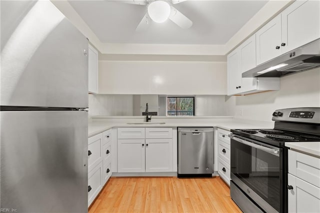 kitchen with under cabinet range hood, stainless steel appliances, a sink, white cabinetry, and light countertops