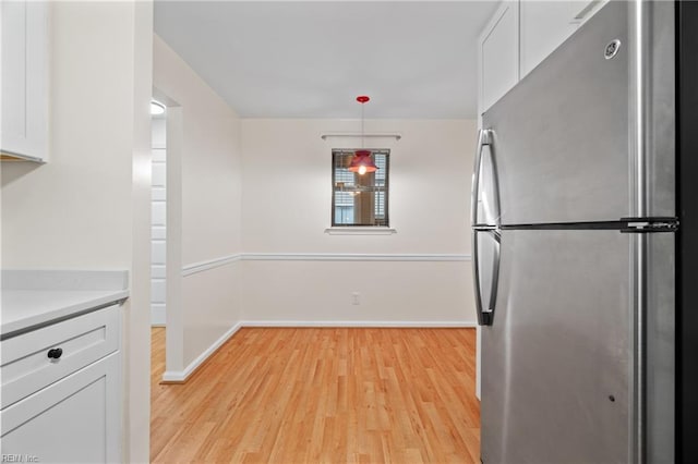 kitchen featuring pendant lighting, white cabinets, light countertops, and freestanding refrigerator