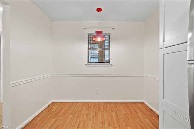 unfurnished dining area with baseboards and wood finished floors