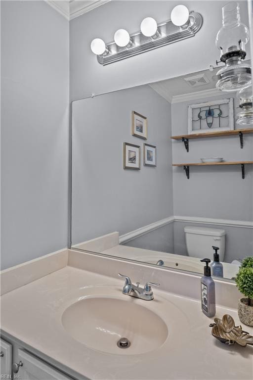 half bath featuring visible vents, vanity, toilet, and crown molding