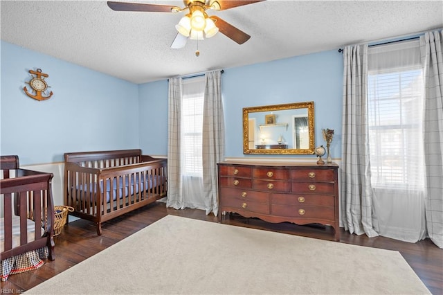 bedroom with a textured ceiling, multiple windows, and dark wood-type flooring