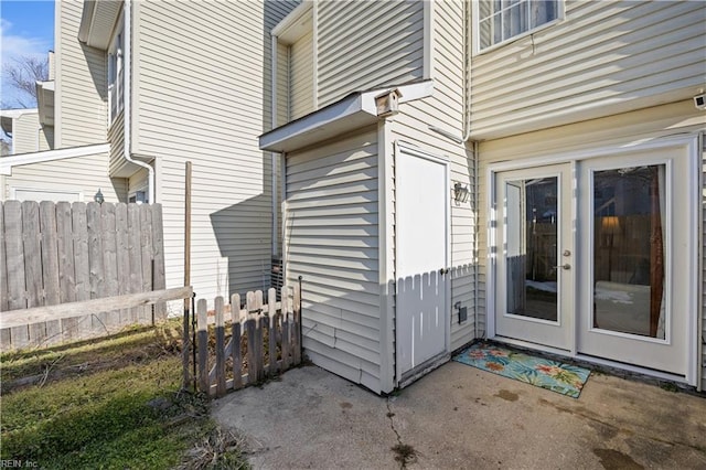 view of exterior entry featuring fence and a patio