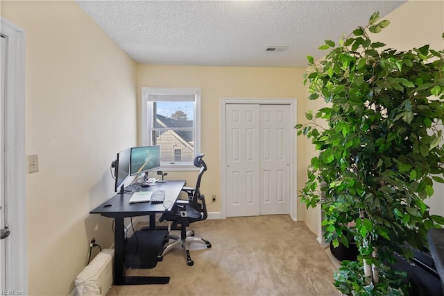 office featuring visible vents, light carpet, and a textured ceiling