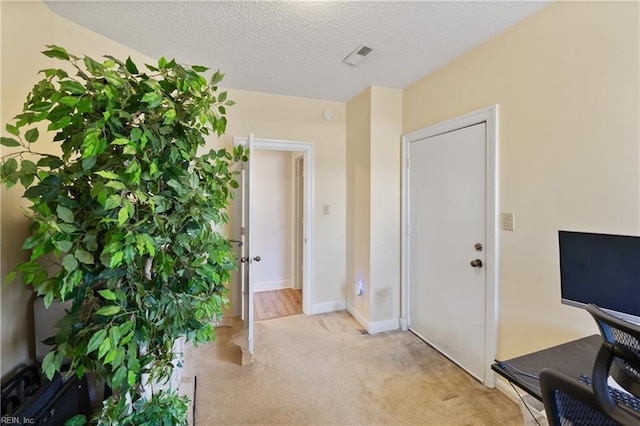 interior space with light carpet, baseboards, visible vents, and a textured ceiling