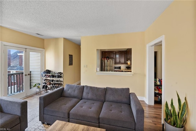 living area with a textured ceiling, french doors, light wood finished floors, and baseboards