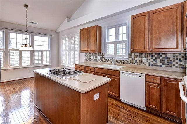 kitchen featuring white dishwasher, a sink, light countertops, brown cabinets, and decorative light fixtures