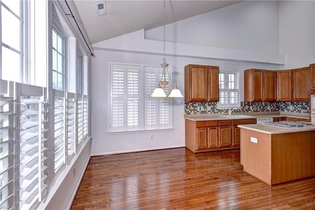 kitchen featuring brown cabinetry, light countertops, a sink, and decorative light fixtures