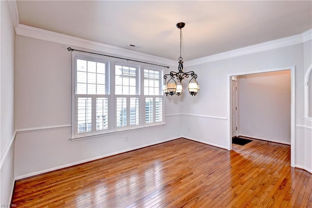 spare room with baseboards, visible vents, ornamental molding, hardwood / wood-style floors, and a chandelier