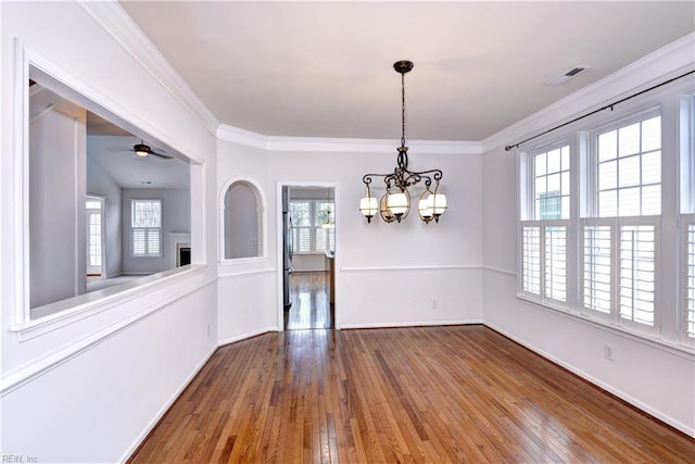 unfurnished dining area with ornamental molding, baseboards, hardwood / wood-style floors, and ceiling fan with notable chandelier