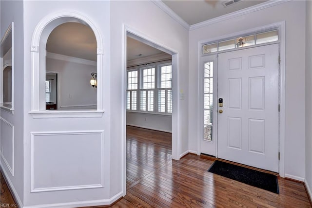 foyer featuring dark wood-style floors, baseboards, ornamental molding, and arched walkways