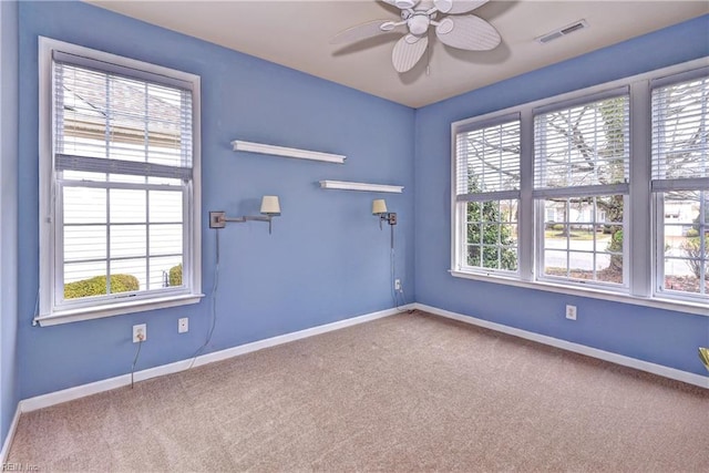 carpeted spare room featuring a ceiling fan, visible vents, and baseboards