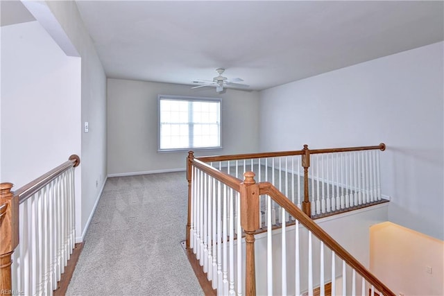 corridor with baseboards, light carpet, and an upstairs landing