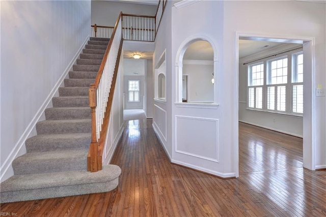 staircase featuring a towering ceiling, baseboards, and hardwood / wood-style floors