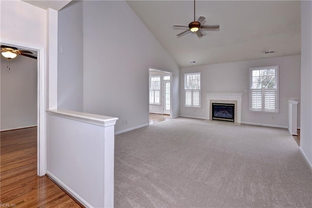 unfurnished living room with ceiling fan, a premium fireplace, visible vents, and a wealth of natural light