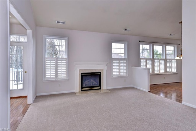 unfurnished living room with a healthy amount of sunlight, visible vents, and a fireplace