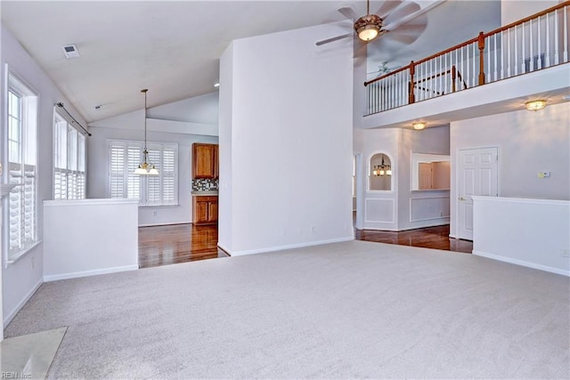 unfurnished living room featuring visible vents, baseboards, ceiling fan, dark carpet, and high vaulted ceiling