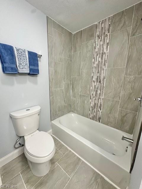 bathroom featuring baseboards, shower / bathing tub combination, a textured ceiling, and toilet