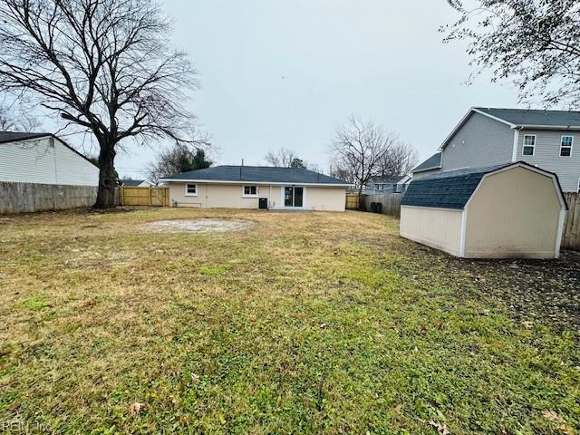 rear view of house featuring a fenced backyard, an outdoor structure, a storage shed, and a lawn