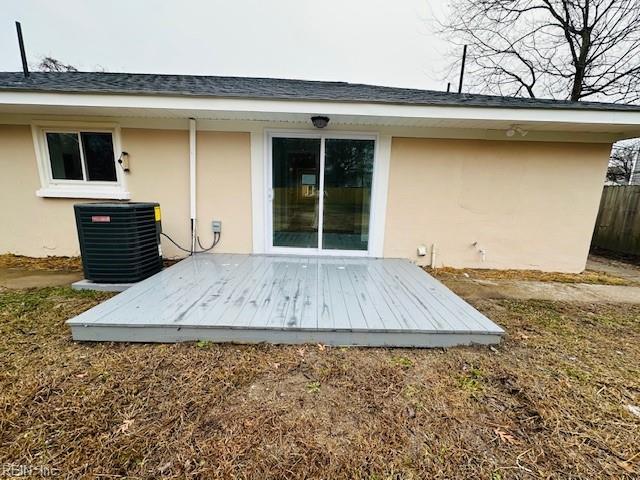 rear view of house featuring central AC unit and stucco siding