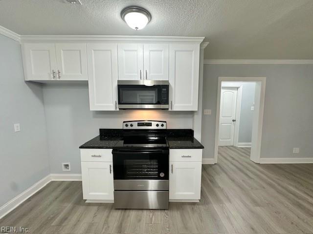 kitchen with appliances with stainless steel finishes, dark countertops, white cabinets, and light wood finished floors