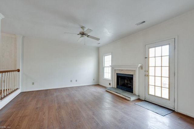 unfurnished living room with a premium fireplace, wood finished floors, a ceiling fan, visible vents, and baseboards