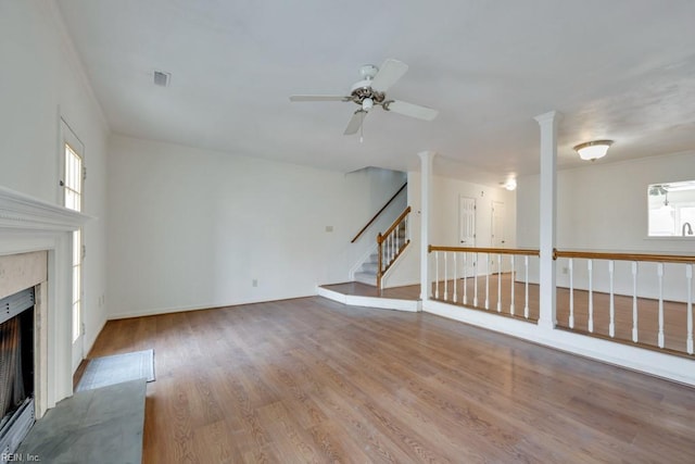 unfurnished living room featuring visible vents, light wood-style flooring, a ceiling fan, a high end fireplace, and stairs