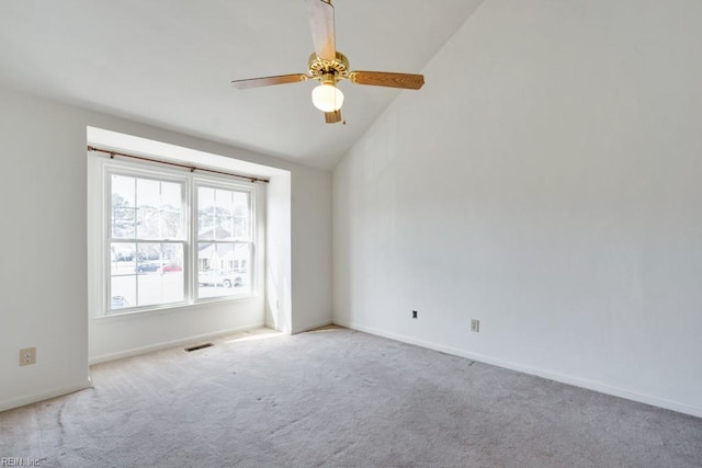 unfurnished room featuring lofted ceiling, ceiling fan, light colored carpet, visible vents, and baseboards