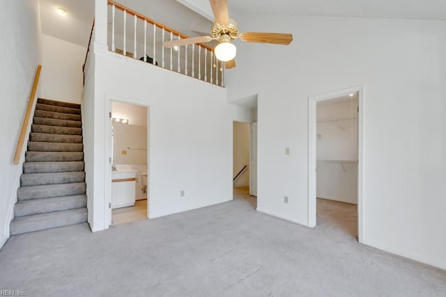 unfurnished bedroom featuring a walk in closet, a closet, a high ceiling, ensuite bathroom, and light carpet