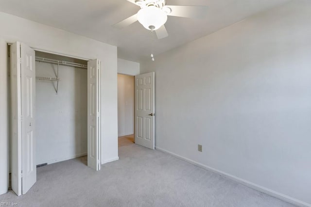 unfurnished bedroom featuring baseboards, ceiling fan, a closet, and light colored carpet