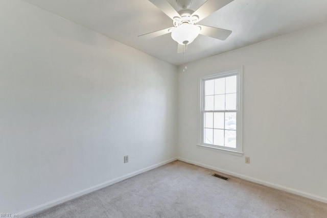 empty room with light carpet, ceiling fan, visible vents, and baseboards