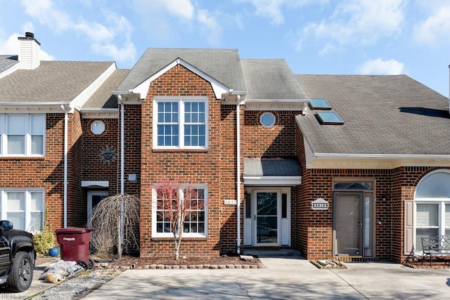 view of property with brick siding and roof with shingles