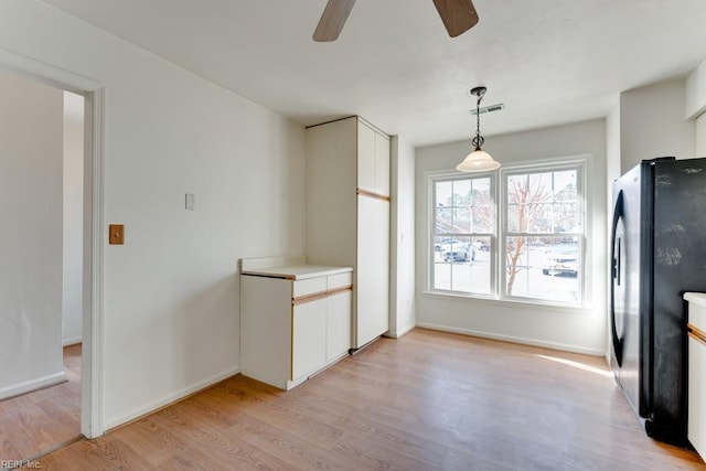 kitchen with visible vents, white cabinets, light countertops, hanging light fixtures, and freestanding refrigerator