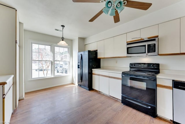 kitchen with black appliances, white cabinetry, light countertops, and decorative light fixtures