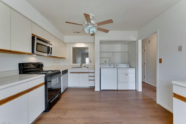 kitchen featuring a sink, white cabinets, light countertops, appliances with stainless steel finishes, and washer and clothes dryer