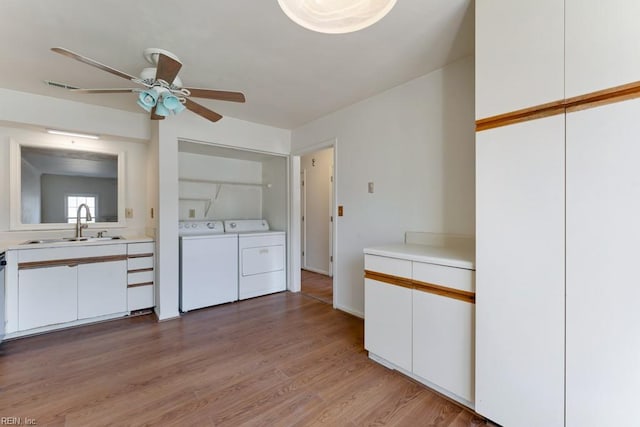 washroom with light wood finished floors, visible vents, washing machine and dryer, a sink, and laundry area