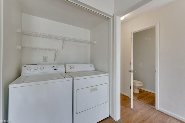 laundry area featuring laundry area, washing machine and dryer, light wood-style flooring, and baseboards