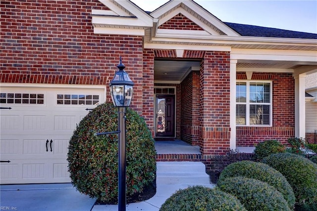 doorway to property with a garage and brick siding