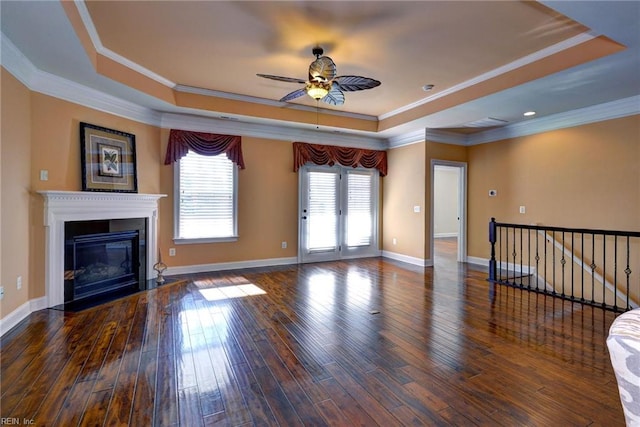 unfurnished living room with a fireplace with flush hearth, dark wood finished floors, baseboards, ornamental molding, and a raised ceiling