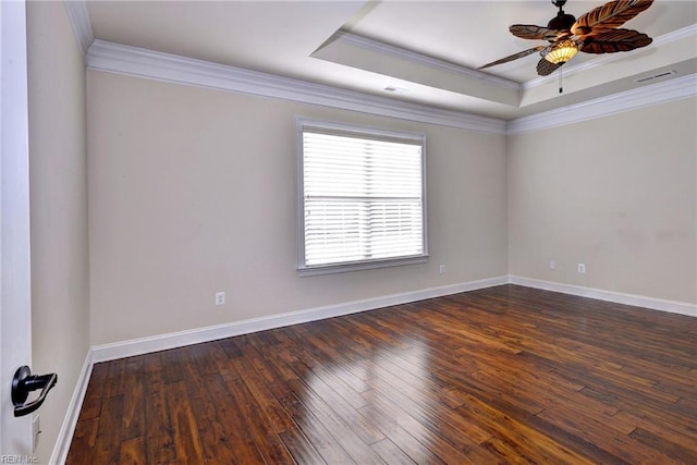 empty room featuring visible vents, baseboards, a tray ceiling, dark wood finished floors, and crown molding