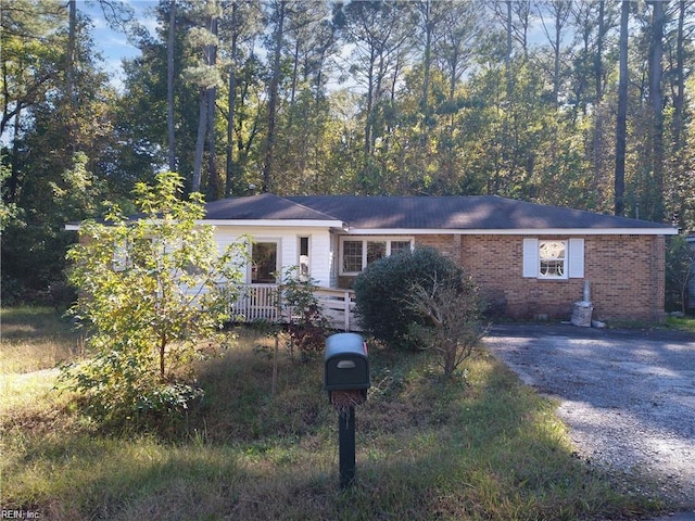 single story home featuring brick siding, a wooden deck, and aphalt driveway