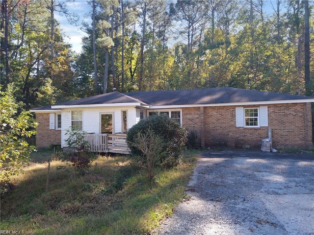 ranch-style house with driveway, brick siding, and a wooden deck