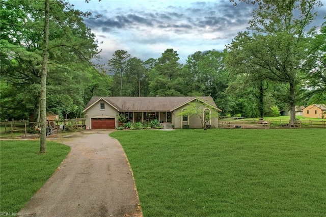 ranch-style house featuring a garage, driveway, fence, and a front yard