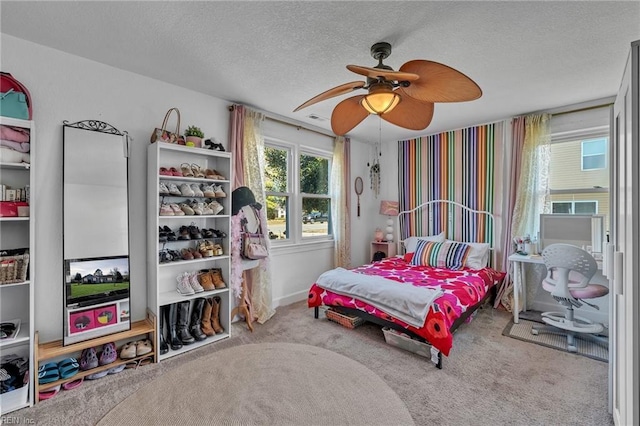 bedroom with a ceiling fan, carpet flooring, and a textured ceiling